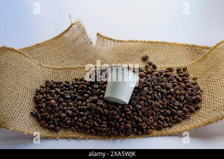 Verstreute Kaffeebohnen und Ausgießen aus einer Kaffeetasse Stockfoto