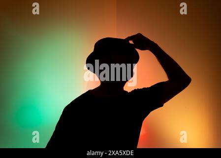 Studio-Porträt eines Mannes, der einen Hut in der Silhouette hält. Isoliert auf farbigem Hintergrund. Stockfoto