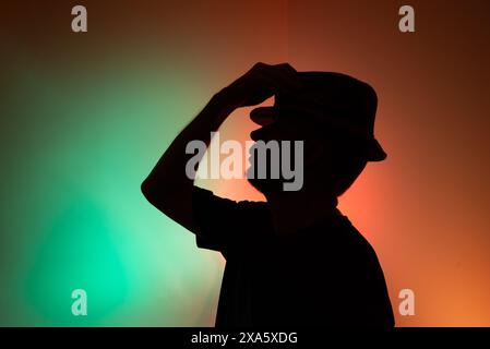 Studio-Porträt eines Mannes, der einen Hut in der Silhouette hält. Isoliert auf farbigem Hintergrund. Stockfoto