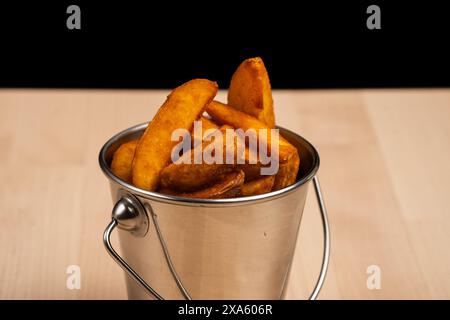 Eine Nahaufnahme eines kleinen Eimers gefüllt mit köstlichen gebackenen Pommes Frites auf einem Tisch Stockfoto