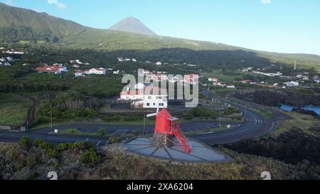 Ein roter Leuchtturm auf einem Felsen überblickt eine Stadt und einen Strand Stockfoto