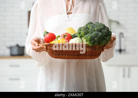 Schwangere Frau, die in der Küche Korb mit unterschiedlichem frischem Gemüse hält Stockfoto