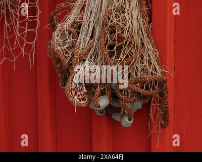 Die Fischernetze hängen an einem roten Boot an einer Wand. Stockfoto