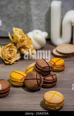 Bunte Macarons und zarte Rosen auf einem Tisch Stockfoto