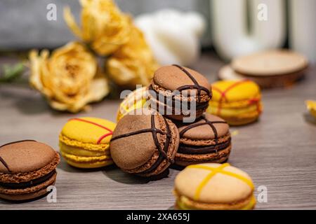 Die farbenfrohen Macarons und zarten Rosen sind auf einem Tisch angeordnet Stockfoto