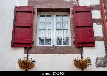 Altes kleines Fenster mit roten Holzläden Stockfoto