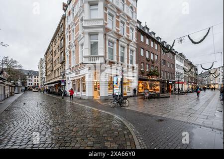 Die Menschen schlendern durch ein historisches europäisches Einkaufsviertel, das mit festlichen Weihnachtslichtern geschmückt ist Stockfoto