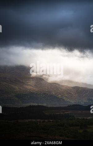 Dunkle Wolken schweben über fernen Bergen Stockfoto