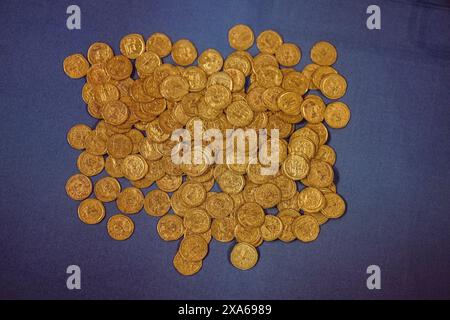 Ein paar kleine Stapel goldener Münzen auf einer blauen Tischplatte Stockfoto
