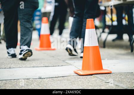 Fußgänger, die an orangefarbenen Kegeln auf der Stadtstraße spazieren Stockfoto