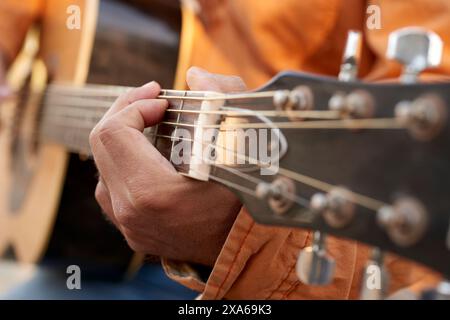 Eine Nahaufnahme von Händen, die eine Akustikgitarre umschlagen Stockfoto