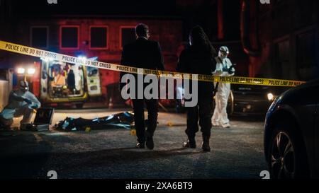 Filmische Aufnahme: Lieutenant kommt an einer Szene an, überquert das gelbe Band, hört Briefing vom First Responder Officer. Detective überprüft den Body Bag. Das Forensik-Team Sammelt Beweise Stockfoto