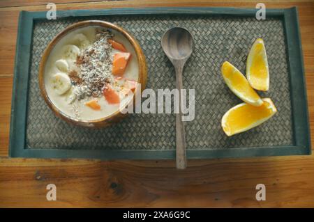 Eine gesunde tropische vegane Frühstücks-Smoothie-Schüssel mit Bananen- und Papaya-Früchten serviert auf einer Holzschale Stockfoto