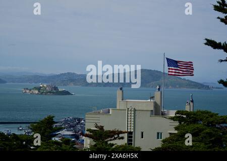 Die US-Flagge schwimmt im Wind mit der San Francisco Bay und Alcatraz Island im Hintergrund Stockfoto