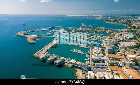 Aus der Vogelperspektive auf Boote, die in einem Hafen mit Stadtgebäuden und Himmel in Limassol Marina, Zypern, angedockt sind Stockfoto