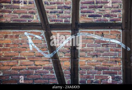 Fassade einer roten Backsteinmauer mit Fachwerkwerk mit weißer Pfeilmalerei. Stockfoto