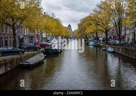 Ein bezaubernder Blick auf einen Kanal, gesäumt von Booten und historischen Gebäuden in Amsterdam, Niederlande. Stockfoto