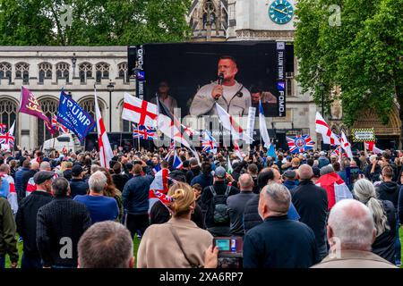 Der politische Aktivist Tommy Robinson, der auf dem großen Bildschirm eine Rede hielt, nach einer Kundgebung gegen die zweistufige Polizei, Parliament Square, London, Großbritannien. Stockfoto