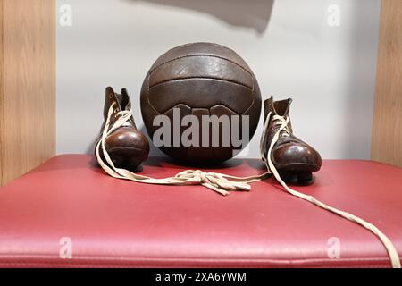 Die Vintage-Sneakers und der Lederball auf roter Ottomane Stockfoto