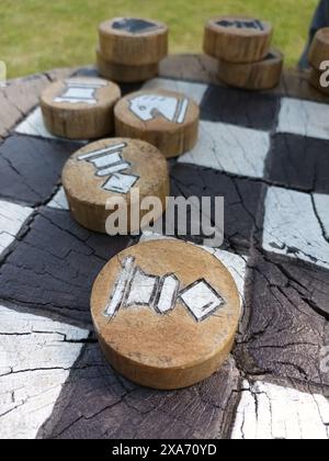 Einige Schachstücke aus Holz werden draußen auf einem großen Brett platziert Stockfoto