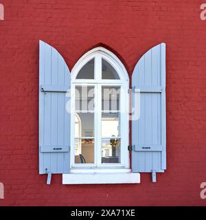 Blick durch die Nahaufnahme eines weiß gerahmten Fensters mit offenen blauen Fensterläden auf das Innere des Fisgard Lighthouse. Stockfoto