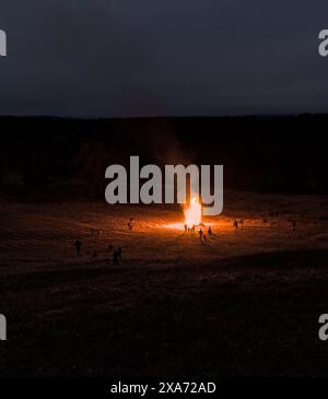 Menschen versammeln sich um ein Lagerfeuer auf einem ländlichen Feld (Winterwärme, Familie feiert gemeinsam) großes Feuer, Flamme, warm (Nacht bei kaltem Wetter) Stockfoto
