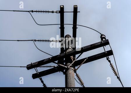 Strommast mit zahlreichen Kabeln gegen bewölkten Himmel Stockfoto