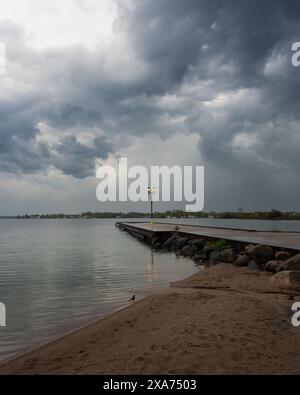 Die dramatischen Sturmwolken ragen über einem einsamen Lichtpfosten auf einem Pier in Orillia, Ontario, Kanada Stockfoto