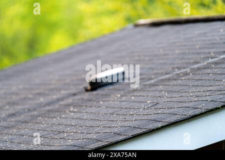 Nahansicht eines Wohndachs mit Asphaltschindeln und einem Entlüftungsrohr. Stockfoto