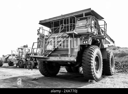 Ein Müllwagen der Armee, der in der Nähe von Maschinen auf unbefestigtem Boden geparkt ist Stockfoto