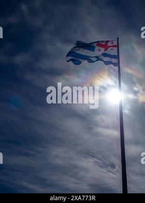 Flagge von Adjara gegen den Himmel. Staatssymbole von Georgien. Die Fahne flattert am Fahnenmast Stockfoto