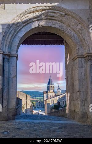 Eine vertikale Aufnahme des historischen Klosters Cluny Abbey durch einen Steinbogen bei Sonnenuntergang in Burgund, Frankreich Stockfoto