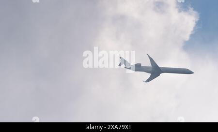 Niedrige Winkelansicht des Flugzeugs, das aus den weißen Wolken fliegt Stockfoto