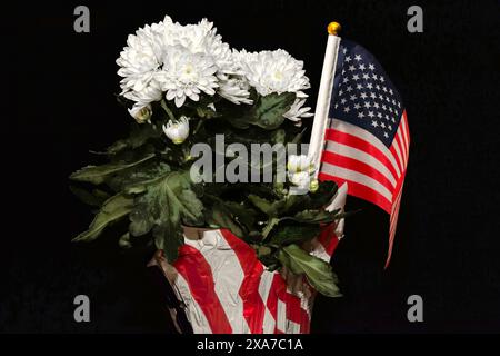 Eine amerikanische Flagge sitzt in einem Blumentopf mit weißen Blumen Stockfoto