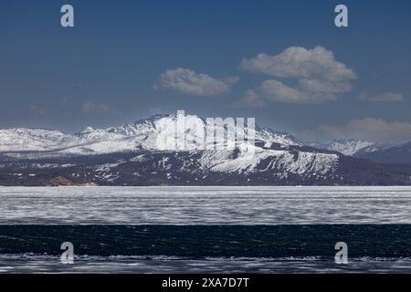 Eine verschneite Bergkette, von einem See aus gesehen Stockfoto