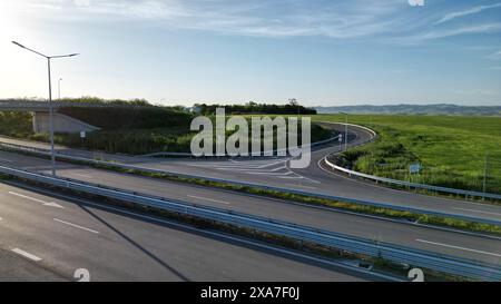 Eine kurvenreiche Autobahn durch üppiges grünes Feld. Stockfoto