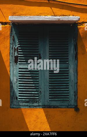 Ein kleines Hausfenster mit blauen Fensterläden Stockfoto