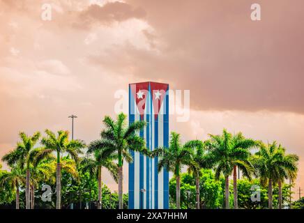 Ein hoher Wolkenkratzer, gemalt als kubanische Flagge an seinen Wänden, ragte neben Palmen unter einem bewölkten Himmel Stockfoto