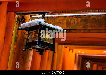 Eine traditionelle japanische Laterne im alten Stil, bedeckt mit seltenem Winterschnee im Torii Gate Tunnel am Fushimi Inari Schrein in Kyoto Japan. Stockfoto