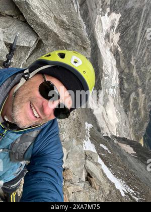 Ein Mann steht auf einem Berg mit Helm und Sonnenbrille in den französischen Alpen Stockfoto