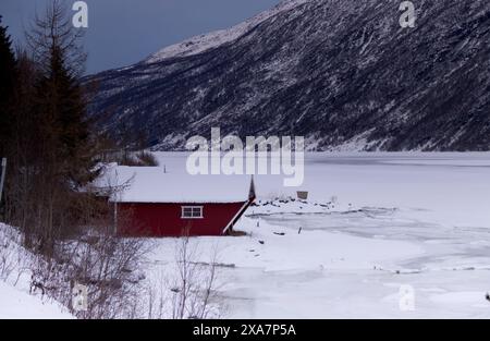 Ein rotes Haus am See in schneebedeckter Landschaft Stockfoto