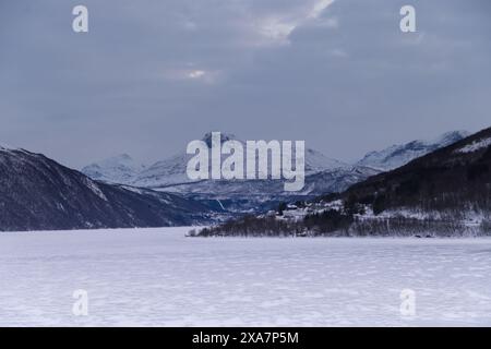 Schneebedeckte Berge, See und in Wolken gehüllte Bäume Stockfoto