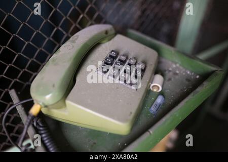 Geringe Schärfentiefe (selektiver Fokus) mit einem alten analogen Telefon, das in einer alten Fabrik mit Staub bedeckt ist. Stockfoto