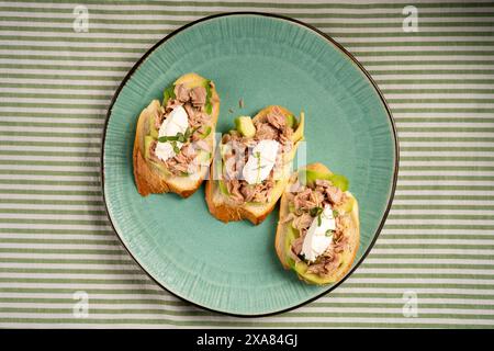 Baguette-Scheiben mit frischem Thunfisch, Frischkäse und gehacktem Zwiebelschnitt auf Marmorbrett. Esstisch mit Weihnachtsmotiv. Stockfoto