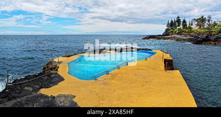 Naturschwimmbad auf Felsen mit Blick auf das Meer und die Klippen unter bewölktem Himmel, Caloura, Ribeira Cha, Sao Miguel Island, Azoren, Portugal Stockfoto