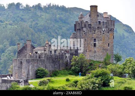 Das beleuchtete Eilean Donan Castle spiegelt sich im Wasser an einem ruhigen Abend, alte Steinbrücke, Drehort für James Bond, Highlander, Rob Roy Stockfoto