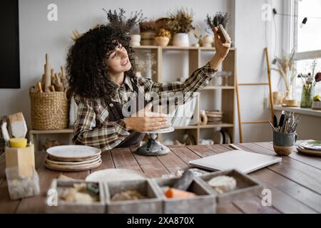 Töpferin, die Töpferhandbuch im Studio aufnimmt Stockfoto