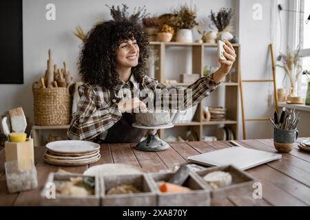 Eine Töpferin macht Selfie, während sie Töpferei im Kunststudio macht Stockfoto