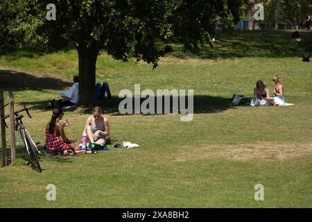 Die Menschen genießen ein heißes Wetter, während einige Sonnenbaden und andere den direkten Sonnenschein in London meiden. Stockfoto