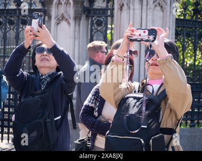 Ostasiatische Touristen vor den Houses of Parliament in Central London, fotografieren mit Mobiltelefonen Stockfoto